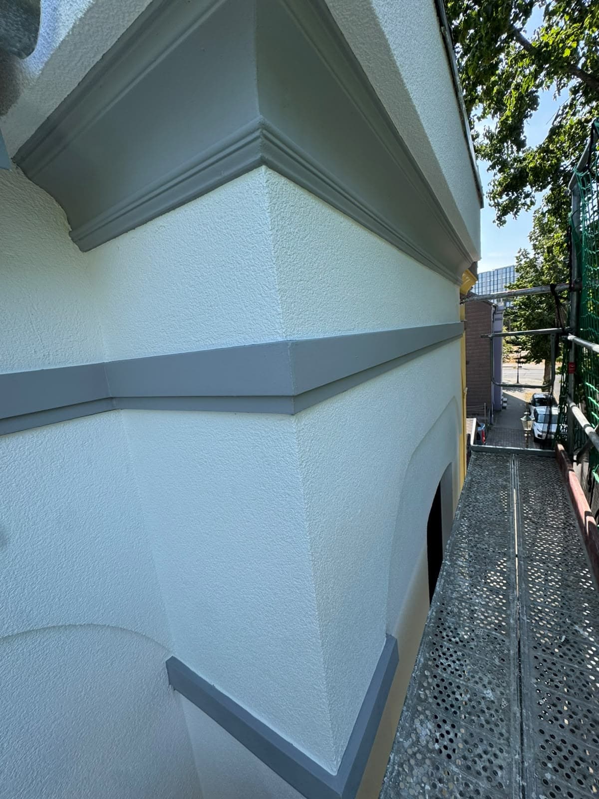 Detailansicht einer Fassade mit Gesims und präzise abgesetzten Putzflächen